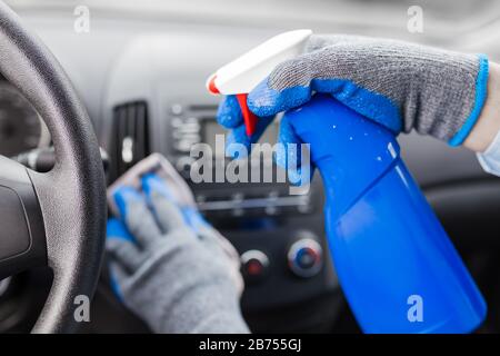 Tableau de bord de voiture nettoyante pour homme et pulvérisation avec liquide de désinfection. Banque D'Images