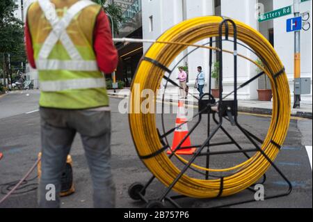 15.04.2018, Singapour, République de Singapour, Asie - un travailleur pose des câbles dans une rue du quartier des affaires. [traduction automatique] Banque D'Images