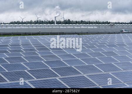 Culture végétale industrielle (tomates, poivrons, concombres) dans une serre moderne et grande près de Feulersdorf en Franconie. En arrière-plan, les éoliennes, au premier plan une ferme solaire, entre l'autoroute. [traduction automatique] Banque D'Images