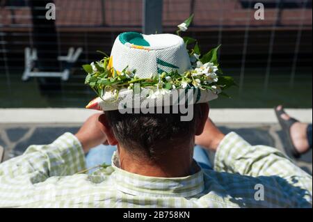 23.06.2018, Helsinki, Finlande, Europe - un homme portant un chapeau décoré de fleurs est assis à la piscine de la mer d'Allas. À l'occasion du milieu de l'été, beaucoup de gens se décorent avec des couronnes de fleurs. [traduction automatique] Banque D'Images