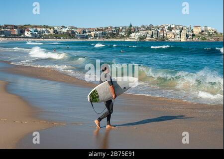 21.09.2018, Sydney, Nouvelle-Galles du Sud, Australie - UN surfeur marche avec son planche de surf sous son bras vers la mer à Bondi Beach. [traduction automatique] Banque D'Images