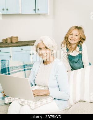 Adorable petite-fille enseigner sa grand-mère Comment jouer sur ordinateur bonne Granny à l'aide de l'ordinateur portable gai Dames joyeuses Smiling pour appareil photo, tonifiée i Banque D'Images