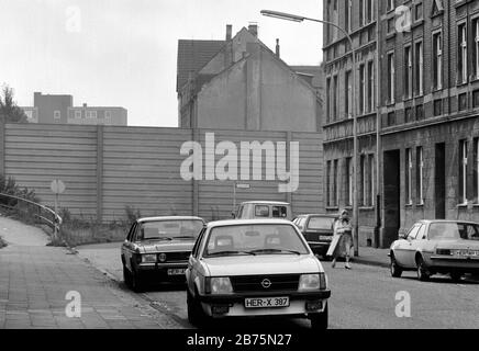 Une femme traverse une route près de l'autoroute A 42 à Herne, un mur de protection contre le bruit est de protéger les maisons voisines du bruit, 12 février 1984. [traduction automatique] Banque D'Images