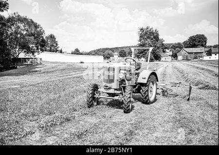 Un tracteur se trouve sur un terrain de Mödlareuth, en Haute-Franconie, à la frontière entre la Bavière et la Thuringe. Jusqu'en 1989, la frontière germano-allemande et le mur des frontières couraient directement au milieu du village, c'est pourquoi les troupes américaines locales l'appelaient "petit Berlin". [traduction automatique] Banque D'Images