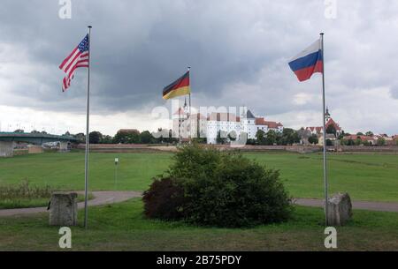 Un drapeau américain, russe et allemand survolera le 06.09.2017 au mémorial "l'Esprit de l'Elbe" à Torgau. Le mémorial sur les rives de la rivière Elbe commémore la rencontre entre les Alliés et les forces soviétiques lors de la seconde Guerre mondiale Le 25 avril 1945, la « poignée de main de Torgau » avec des soldats américains et russes a eu lieu ici. Château de Hartenfels en arrière-plan. [traduction automatique] Banque D'Images