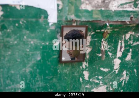 28.01.2017, Yangon, région de Yangon, République de l'Union du Myanmar, Asie - le visage d'un jeune homme se reflète dans un petit miroir sur le côté de la route. [traduction automatique] Banque D'Images