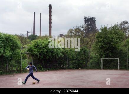 Un garçon joue au football sur un terrain de cendre à Duisburg-Marxloh à l'usine ThyssenKrupp Schwelgern le 21 avril 2017. Avec un taux de chômage de 13%, janvier 2017, et une part des étrangers de près de 20%, la ville de Duisburg est confrontée à de grands problèmes sociaux. [traduction automatique] Banque D'Images