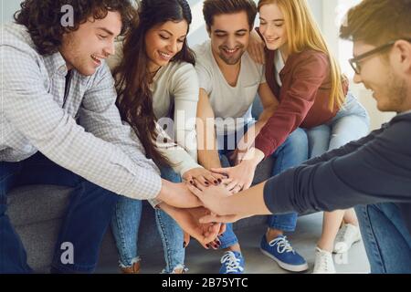 Les amis heureux ont gentièrement levé les mains dans une chambre avec une fenêtre. Banque D'Images