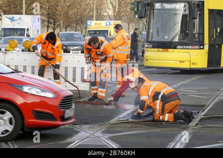 Le 16.12.2016, les travailleurs de la construction de voies travaillent à genoux et remplissent un passage à niveau à un carrefour routier avec de l'asphalte. [traduction automatique] Banque D'Images