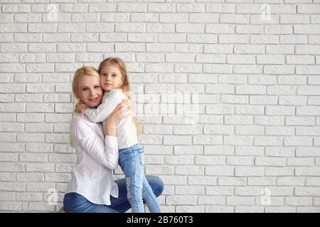 Joyeuses pâques. Mère et fille avec des oreilles de lapin souriant contre un mur de briques blanches. Banque D'Images