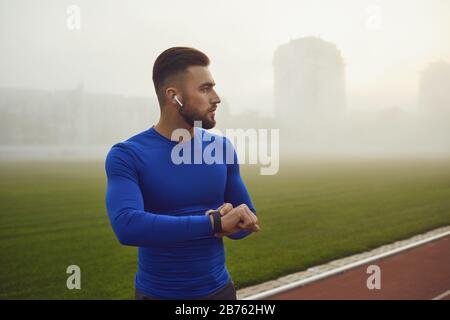 Portrait d'un jeune athlète masculin heureux au stade dans le brouillard. Banque D'Images