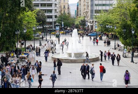 Vue sur la place animée Syntagma avec fontaine au milieu d'Athènes le 11.04.2016. Sur la place Syntagma se trouve le Parlement grec et, de l'autre côté, une rue commerçante populaire. [traduction automatique] Banque D'Images