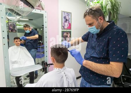 Ferrara, 13 Mars 2020. Un coiffeur travaille dans son salon de coiffure portant un masque de sécurité et des gants en raison de l'urgence du coronavirus à Ferrara, en Italie. Crédit: Filippo Rubin / Alay Live News Banque D'Images