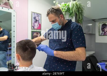 Ferrara, 13 Mars 2020. Un coiffeur travaille dans son salon de coiffure portant un masque de sécurité et des gants en raison de l'urgence du coronavirus à Ferrara, en Italie. Crédit: Filippo Rubin / Alay Live News Banque D'Images