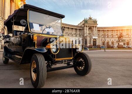 Vienne, Autriche - 12 janvier 2020: Visite de voiture électrique style rétro vintage véhicule pour la visite de la ville touristique contre le palais hofburg de Vienne avec Banque D'Images