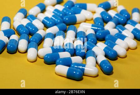 Comprimés de comprimés de comprimés de comprimés de couleur bleue et blanche gélules médicaments macro de médecine gros plan isolé sur fond jaune. Banque D'Images