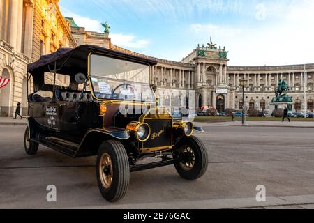 Vienne, Autriche - 12 janvier 2020: Visite de voiture électrique style rétro vintage véhicule pour la visite de la ville touristique contre le palais hofburg de Vienne avec Banque D'Images