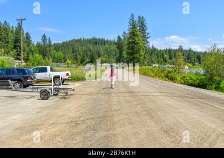 Une femme marche seule sur une route de terre dans les montagnes rurales du nord de l'Idaho. Banque D'Images