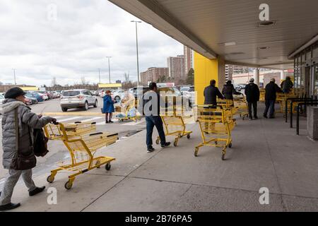 Toronto, Canada. 13 mars 2020. Les clients qui attendent à l'extérieur d'entrer dans l'épicerie No Frills du centre commercial Center point Mall de North York alors que le magasin tente de contrôler le trafic lourd et un nombre croissant de clients d'acheter de la nourriture et de l'approvisionnement en raison de COVID-19 et de nombreux arrêts dans la ville de Toronto. Dominic Chan/Eximages Crédit: Eximages/Alay Live News Banque D'Images