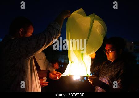 Jaipur Inde, Circa 2020 - Photographie de personnes tenant une lanterne jaune avec les flammes montrant clairement. La lanterne du ciel est tenu par 3 personnes attendent Banque D'Images