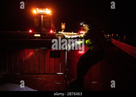 Petrovice, République Tchèque. 13 mars 2020. Un employé de la société tchèque d'entretien d'autoroutes tire une barrière sur la chaussée de la jonction Petrovice sur l'autoroute D8 Dresden - Prague. La République tchèque ferme en grande partie ses frontières aux étrangers de plusieurs pays européens. Entre autres, les citoyens d'Allemagne, d'Italie, de France et d'Autriche qui n'ont pas de résidence permanente dans l'État membre de l'UE sont affectés. Crédit: Sebastian Kahnert/Dpa-Zentralbild/Dpa/Alay Live News Banque D'Images