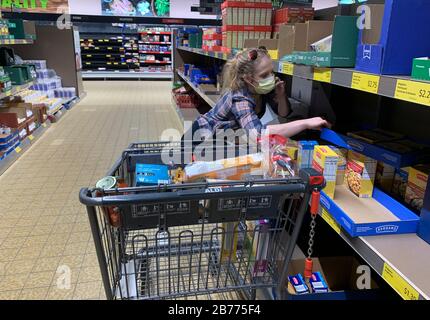 Bloomington, États-Unis. 13 mars 2020. Une femme recueille de la nourriture après que les acheteurs aient paniqué acheter de la nourriture dans une épicerie Aldi à Bloomington. La femme de droite a dit : « J'ai trois enfants, je dois faire ce que j'ai à faire. » le président américain Donald J. Trump a déclaré une urgence nationale quelques heures plus tôt. Crédit: Sopa Images Limited/Alay Live News Banque D'Images