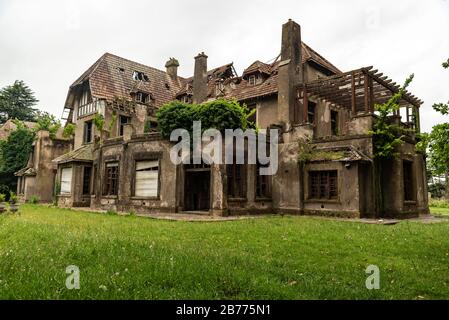 Ancienne maison abandonnée qui a pris feu avec un jardin vert et un ciel nuageux Banque D'Images