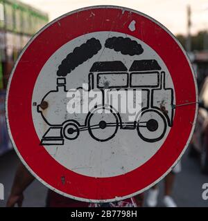 Ancienne affiche en forme de rond aux couleurs rouge et noir blanc, indiquant qu'un train y passe Banque D'Images