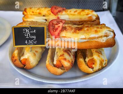 Une pile de sandwichs hot dog dans des petits pains de baguettes recouverts de fromage fondu est exposée dans un magasin de sandwichs local à Nice, France Banque D'Images