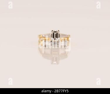 Un anneau d'engagement de solitaire en diamant de style émeraude de tiffany avec des baguettes de chaque côté, associé à un groupe de mariage de trois baguettes, les deux anneaux Banque D'Images