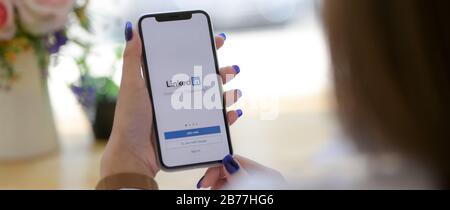 CHIANG mai, THAÏLANDE - 13 MARS 2020 : femme tenant iPhone avec écran Linkedin. LinkedIn est une application mobile pour rechercher des opportunités de carrière Banque D'Images