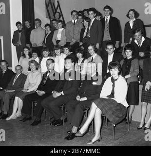 Années 60, historique, groupe de jeunes enthousiastes dans une salle de village ayant une photo avec des invités distingués, y compris le maire et les prêtres locaux, Angleterre, Royaume-Uni. Banque D'Images