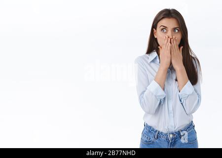 La jeune femme stupéfiée et choquée a entendu des informations choquantes, se ragotant au bureau, se couvrir la bouche avec les mains tout en se déversant de l'étonnement, regarder à gauche Banque D'Images