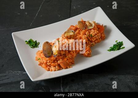 Risotto aux fruits de mer - Rise italienne typique avec sauce tomate et fruits de mer - photo studio horizontale Banque D'Images