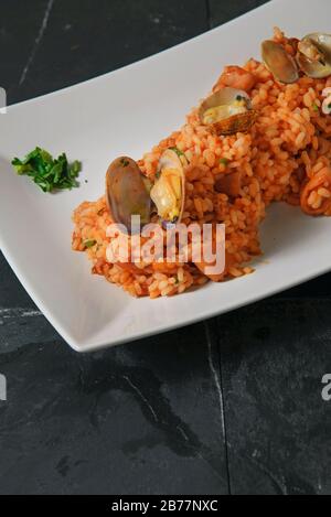 Risotto aux fruits de mer - Rise italienne typique avec sauce tomate et fruits de mer - photo studio verticale Banque D'Images