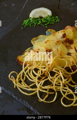 Sea ​​bream dans la croûte de pommes de terre avec oignon haché frit - photo studio verticale Banque D'Images