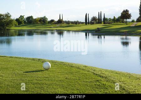 Balle de golf sur le vert avec un ton chaud et coucher de soleil Banque D'Images