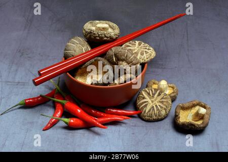 Champignons shiitake séchés dans un bol, des chilis et des baguettes rouges, Allemagne Banque D'Images