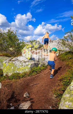 Deux jeunes garçons montant une montagne sur un chemin de terre. Jour d'été ensoleillé. Seulement dans les shorts et les chaussures, pas de t-shirts. Banque D'Images