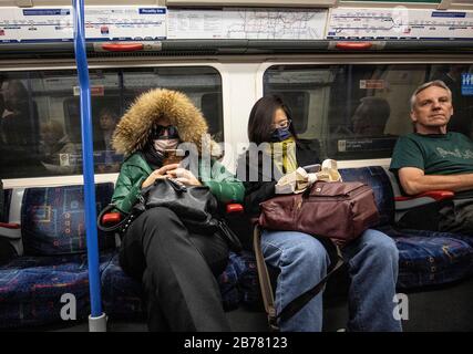 Métro de Londres, Royaume-Uni. 14 mars 2020. Les touristes portant des masques de protection contre le Coronavirus (covid-19) liste de whlist voyageant sur le métro de Londres, Angleterre, Royaume-Uni crédit: Clickpics/Alay Live News Banque D'Images