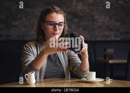 Photographe jeune femme vérifiant une image dans une cafétéria Banque D'Images