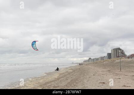 Oostduinkerke, Belgique - 26 février 2020: Kitesurfer reposant sur la plage pendant une journée froide et venteuse Banque D'Images