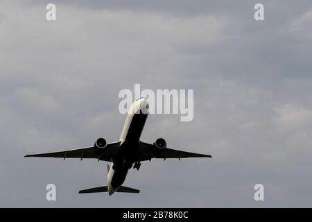 Avion volant à travers le ciel nuageux. Avion en hauteur en silhouette avec un fond bleu ciel. Transport moderne et aviation. Jet d'air passager Banque D'Images