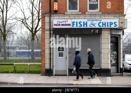 Les gens à l'extérieur de la rue fermée Maine Road chippy près du stade Etihad, stade du club de football de Manchester City, suite à l'annonce d'hier que la Premier League a suspendu tous les matches jusqu'au samedi 4 avril 2020. Banque D'Images