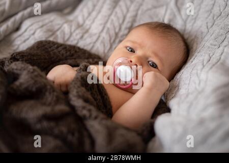Jolie fille avec sucette enveloppée dans une couverture Banque D'Images