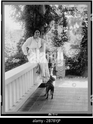 Geraldine Farrar, portrait complet, assis sur le porche, face légèrement à droite; chien sur le porche) - Hartsook photo, S.F.-L.A Banque D'Images