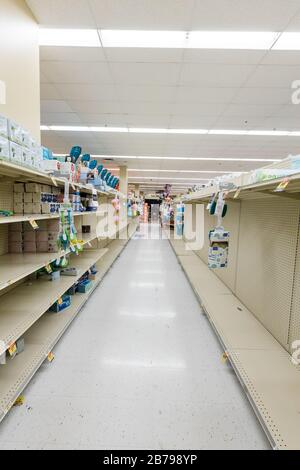 Vider les étagères dans une épicerie de supermarché dans l'allée de l'eau en bouteille car le coronavirus provoque la peur et la panique Banque D'Images