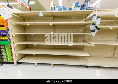 Presque vide étagères dans une épicerie de supermarché dans l'allée d'eau en bouteille car le coronavirus provoque la peur et la panique Banque D'Images