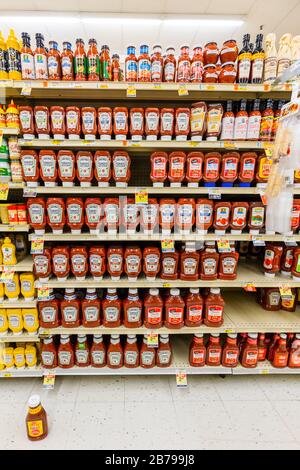 Heinz et d'autres marques de bouteilles de sauce au ketchup de tomates rouges entièrement stockées sur des étagères de l'allée de condiments dans le supermarché magasin vertical d'épicerie Banque D'Images