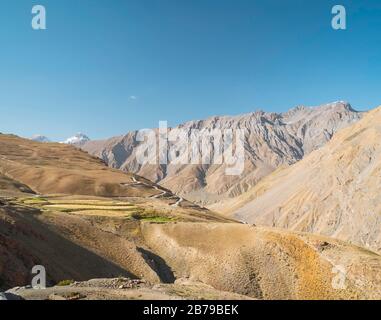 Paysage accidenté des montagnes de l'Himalaya avec des pics et des crêtes sous le ciel bleu clair avec à peine des champs visibles dans le milieu du sol près de Kibber, Himach Banque D'Images